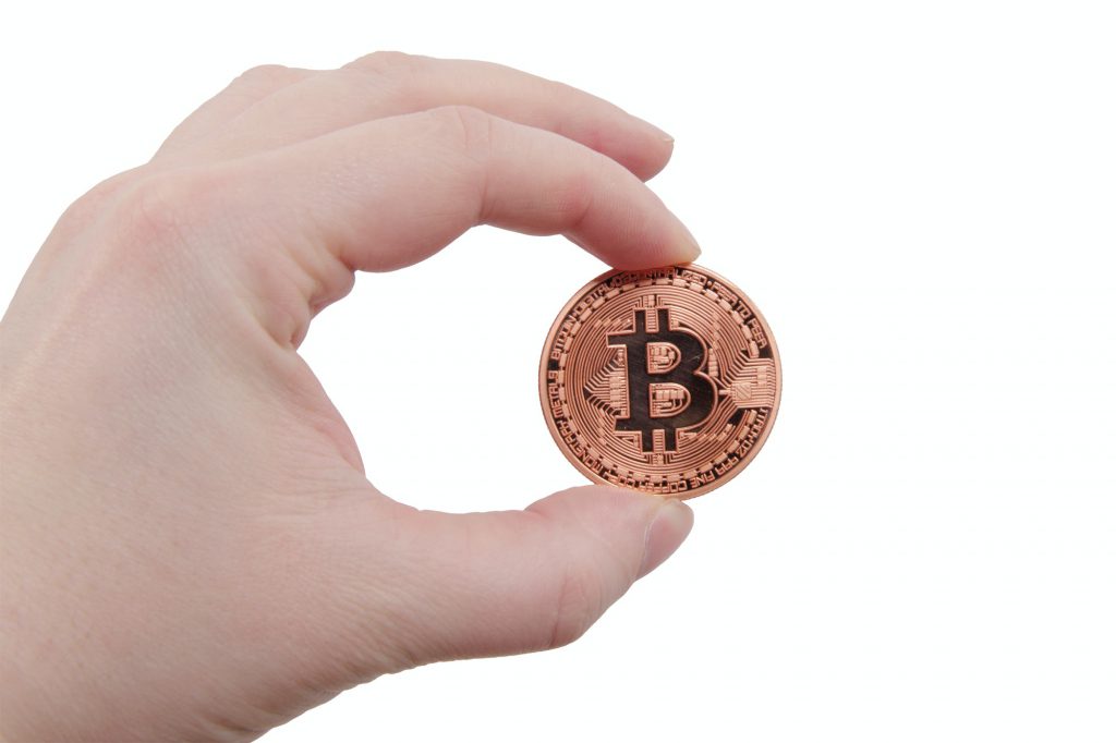 Bitcoin coin in a hand on a white background